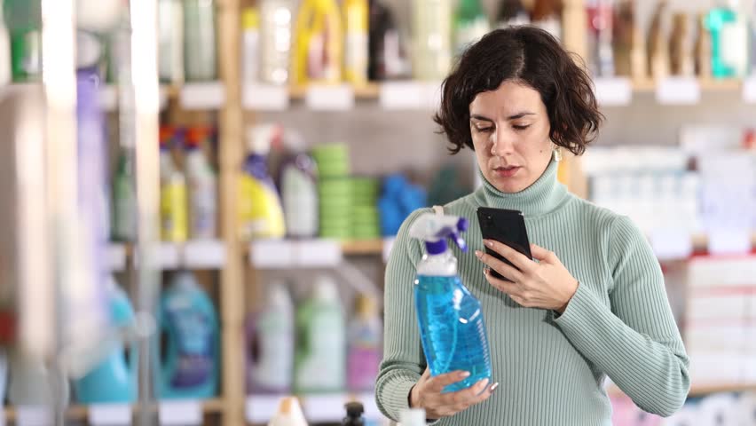 Adult woman buyer scanning qr code for cleaning spray in household chemicals store