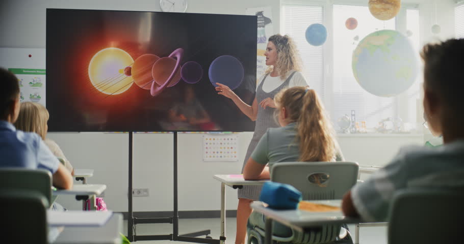 Astronomy Class: Female Teacher Explaining Solar System to Primary School Children Using Digital Screen. Group of Young Boys and Girls Sitting at the Desks, Learning Space Science in Modern Classroom.