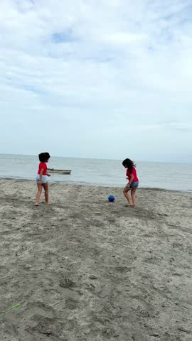 Two girls enjoy a friendly soccer match on a beautiful beach