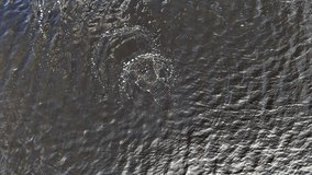 Concentric air bubbles rise and burst on rippled water as a submerged diver moves below, seen from a steady overhead drone, suggesting depth, search training, and quiet suspense. - Powered by Shutterstock - Get 15% off with code: PIKWIZARD15