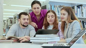 Cheerful young adult university students studying at library using books and laptop, talking and smiling while working on group project - Powered by Shutterstock - Get 15% off with code: PIKWIZARD15