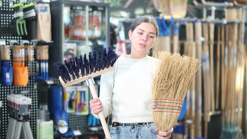 European woman chooses a large broom and a brush for the garden. Customer on sale in a garden store for the summer season. High quality 4k footage