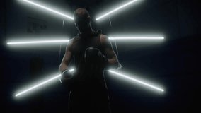 Silhouette of man putting on boxing gloves getting ready for fight with light behind him. Sports concept. Slow motion video 4K - Powered by Shutterstock - Get 15% off with code: PIKWIZARD15