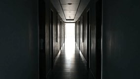 A dimly lit hotel corridor with multiple doors on both sides, leading to a bright light at the end. The contrast between shadow and light creates a dramatic architectural perspective. - Powered by Shutterstock - Get 15% off with code: PIKWIZARD15