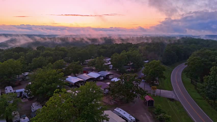 An RV park in Branson, Missouri is covered by low-hanging clouds and a bright sunset.