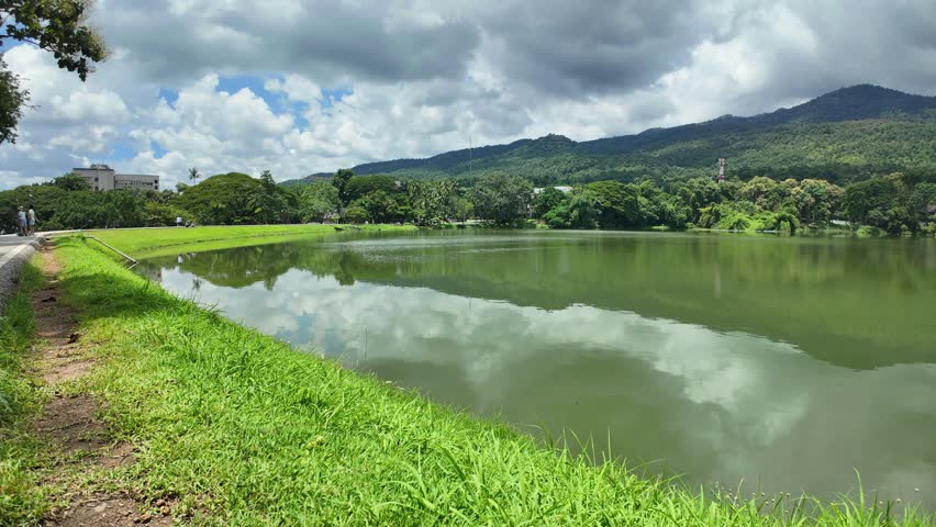 4K Time lapse of a public place leisure travel landscape lake views at Ang Kaew Chiang Mai University and Doi Suthep nature forest Mountain views spring cloudy sky background with white cloud.