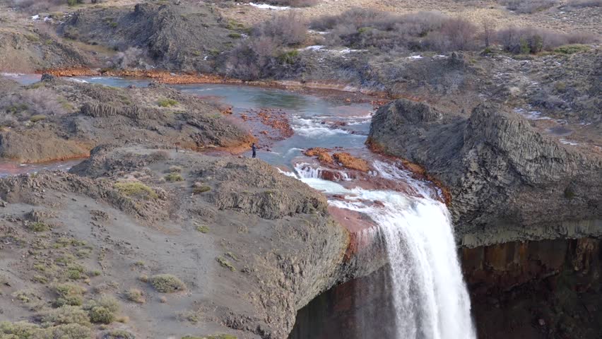 Approaching aerial fly to the Salto del Agrio waterfall top side where flowing the river between rocky environment, Neuquén, Argentina.
