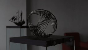 A decorative metal wire sculpture placed on a glass and wood table in a modern living room. Contemporary interior design element with chairs and minimalist decor in the background. - Powered by Shutterstock - Get 15% off with code: PIKWIZARD15