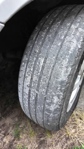 heavily worn car tires. Worn old tires on a car close-up. Vehicle tire driving over a damaged highway which is covered in Potholes in the street. POV camera attached to side