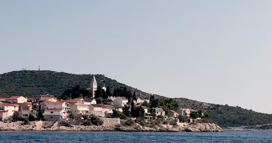 Beautiful panoramic view of the seaside town Primošten in Croatia. Traditional Mediterranean houses and a church tower sit on a peninsula surrounded by calm Adriatic waters.