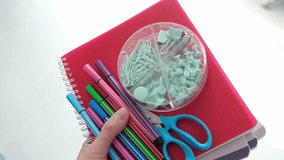A person is holding a red notebook with a green section in the middle. The notebook is filled with colorful pens and scissors - Powered by Shutterstock - Get 15% off with code: PIKWIZARD15