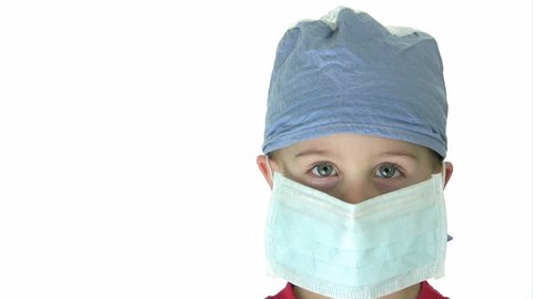 Kid wearing surgeon's gear, removes the mask and hat while smiling.  HD 1080i