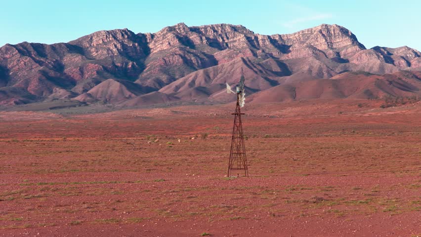 Drone telephoto shot with enlarged Flinders Ranges mountains behind isolated windmill, South Australia