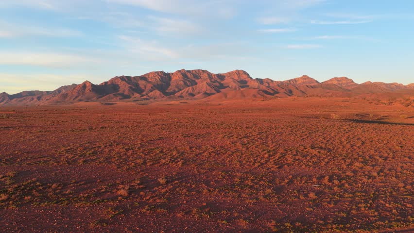 Drone pulls back to show windmill and vibrant red landscape in Flinders Ranges, South Australia