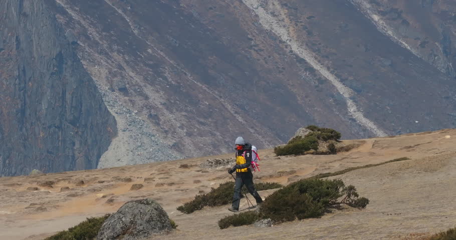Drone shot of a female tourist hiking in Nepal’s Khumbu region toward Everest Base Camp. Mt. Cholatse stands in the backdrop, framing a wide Himalayan landscape of adventure, travel, and tourism