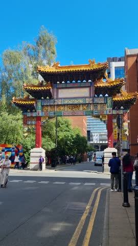 Manchester , North West England , United Kingdom (UK) - 08 02 2025: Vertical shot of the Chinese town gate in the city center, with a crowd of tourists photographing the landmark on a sunny summer day