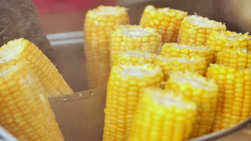 Street vendor cooking corn on the cob in a large pot