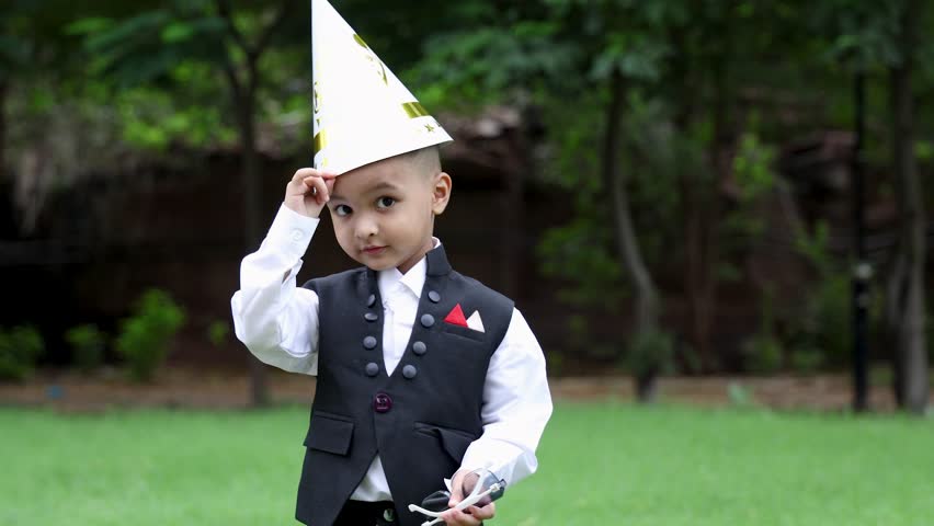 cute indian toddler well dressed up with awe expression and birthday cap at outdoor