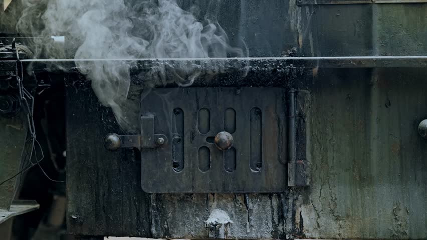 Smoke rises from old metal stove door in gritty WWII field kitchen setting