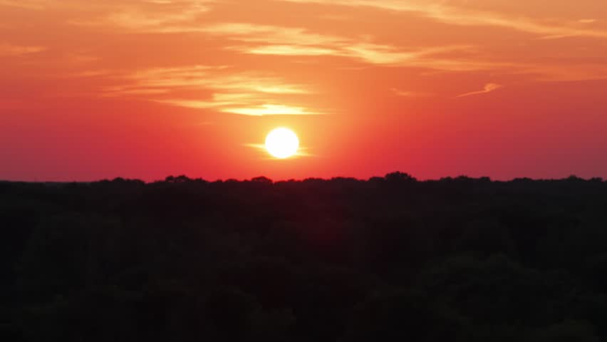 Telephoto close-up aerial dolly shot of a vibrant sunset on a Minnesota lake. 4K