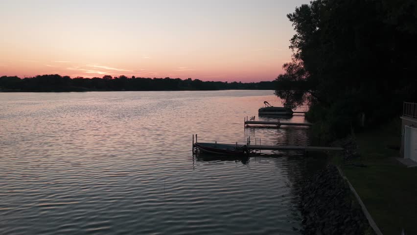 Low aerial shot flying over docked fishing and pontoon boats at sunset on a lake in Center City, Minnesota. 4K