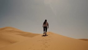 Person walks alone along the crest of a sand dune under the midday sun in Merzouga, Sahara Desert, Morocco. - Powered by Shutterstock - Get 15% off with code: PIKWIZARD15