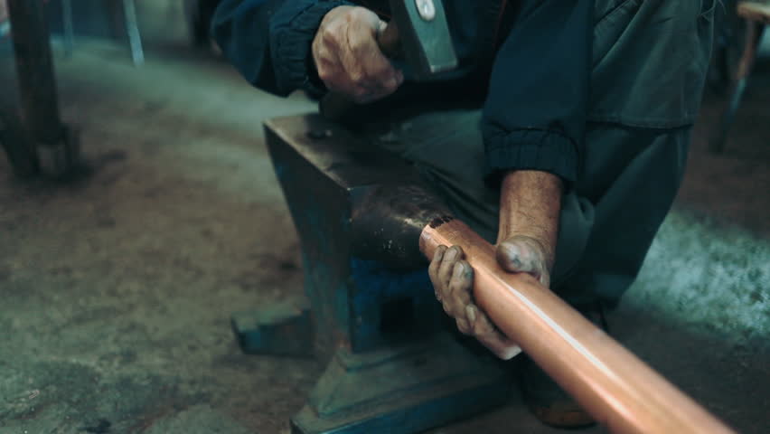 Traditional coppersmith workshop for copper brewing pots manufacturing. This handmade brewery kettles will be used for making traditional alcohol brandy drinks. Small traditional business concept.
