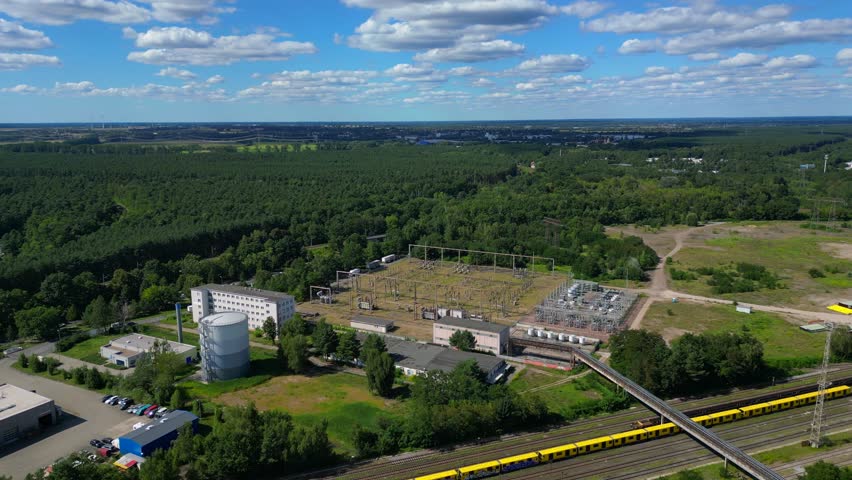 Hennigsdorf substation, distributing electricity and surrounded by a lush green forest in Brandenburg, Germany. Unique aerial view flight panorama orbit drone