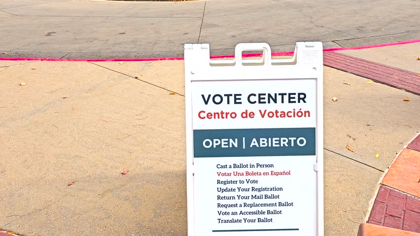 Close-up shot of a “Vote Center, Centro de Votación – Open, Abierto” sign with Spanish translation, symbolizing inclusive democracy, in-person voting access, voter registration, and mail ballots.