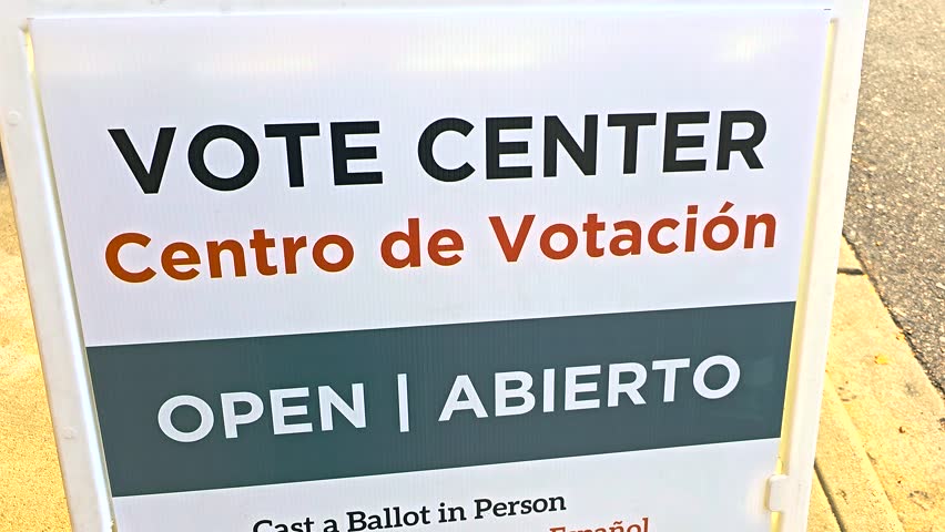Outdoor bilingual signage “Vote Center – Open, Abierto” and Spanish translation “Centro de Votación,” emphasizing civic engagement through in-person voting, registration, and mail ballot returns.
