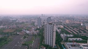 Aerial drone shot flying directly towards multi floor skyscraper apartment building with massive balconies surrounded by pwoer distribution, smaller villas and city scape in distance - Powered by Shutterstock - Get 15% off with code: PIKWIZARD15