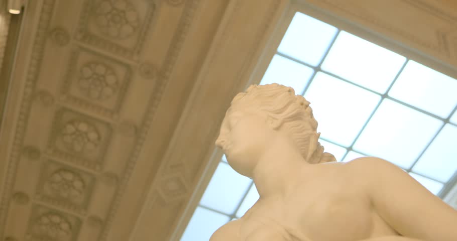 Trieste museum scene: slow orbit around a classical marble statue beneath a skylit ceiling. Soft daylight, neoclassical details and serene gallery ambiance create a refined art shot