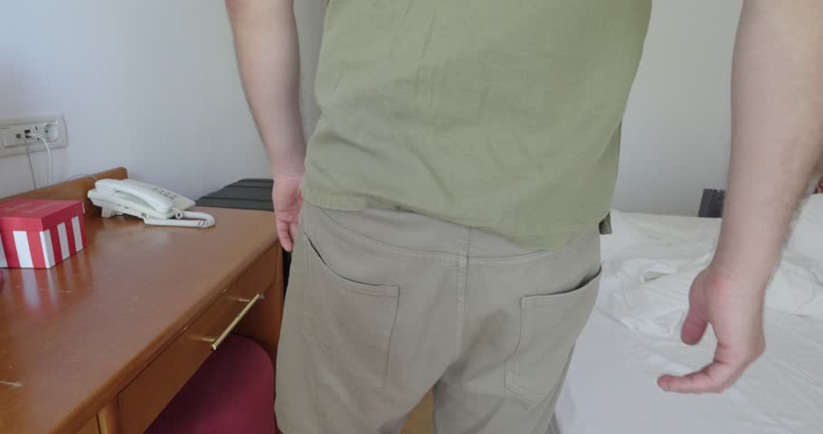 A man in casual clothes rushes towards the bathroom, holding his backside in urgency. Typical gesture illustrates stomach pain, diarrhea or sudden need for toilet.