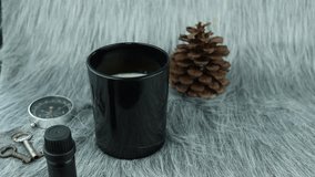luxury aromatic scented candle black glass is light on grey carpet with essential oil, compass and pine cone in bed room to create relax winter cozy ambient on Christmas party with family members  - Powered by Shutterstock - Get 15% off with code: PIKWIZARD15