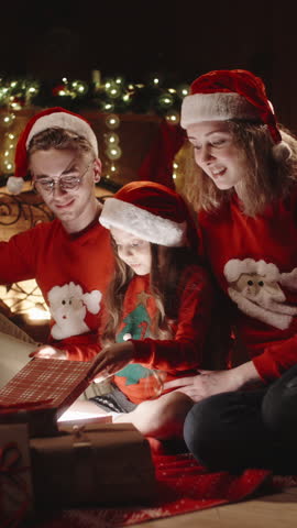 Happy family opening magical Christmas gift in cozy living room