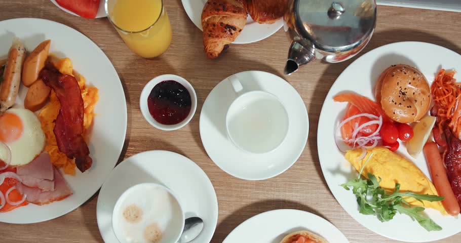 Hearty breakfast spread on table with bacon, eggs, croissants, juice, coffee, and jam. Perfect for culinary, hospitality, brunch concepts, showcasing fresh, diverse morning meals.