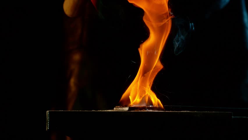 Cinematic close-up of blacksmith forging glowing hot iron on anvil with sparks flying. Shot in dramatic lighting on dark background with high-speed camera at 1000fps. Speed ramp effect.