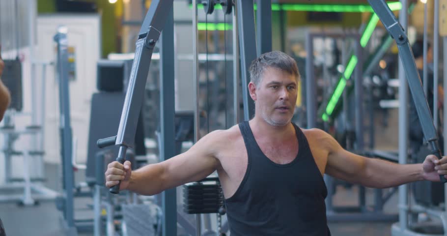 Gym workout. Butterfly exercise. Middle aged Caucasian man trains his pectoral muscles in the gym. Dedicated man strengthens chest muscles with butterfly workout at the gym.