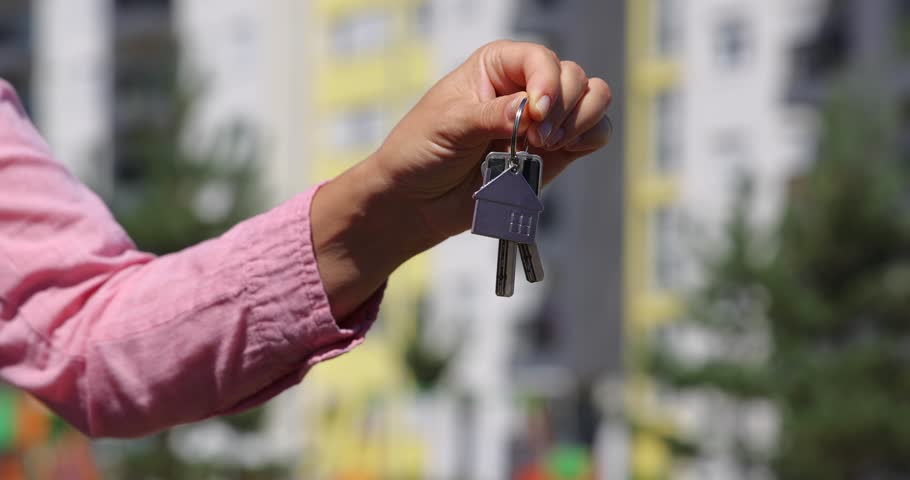 The female owner of the real estate hands over the keys to the new apartment to a young man, and they shake hands. Both are satisfied—they’ve successfully closed the deal. Close up - low angle