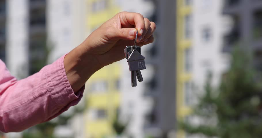 The female owner of the real estate hands over the keys to the new apartment to a young man. Both are satisfied—they’ve successfully closed the deal. Close up - low angle