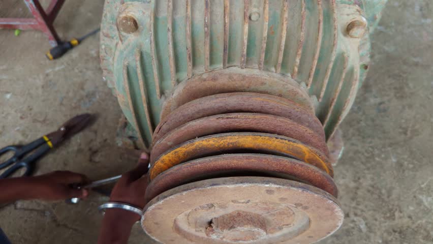 Electrician Fixes Corroded Motor with Wrench, Rotary Pump Restoration at Industrial Garage, Manual Work on Old Electrical Equipment, Rusty Engine Bolt Tightening in Workshop, Adjust Worn Out Machinery