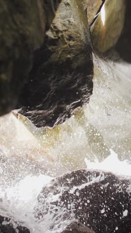 Water droplets after the wave flow down and drip from the rocks in the cave. Vertical format