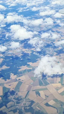 Expansive farmland stretching beneath billowing cumulus clouds, revealing serene agricultural landscape from soaring aerial perspective