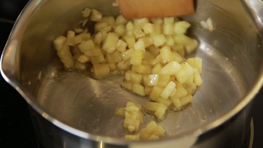 Stirring chopped apples with cinnamon in a saucepan for the filling of pita sandwich