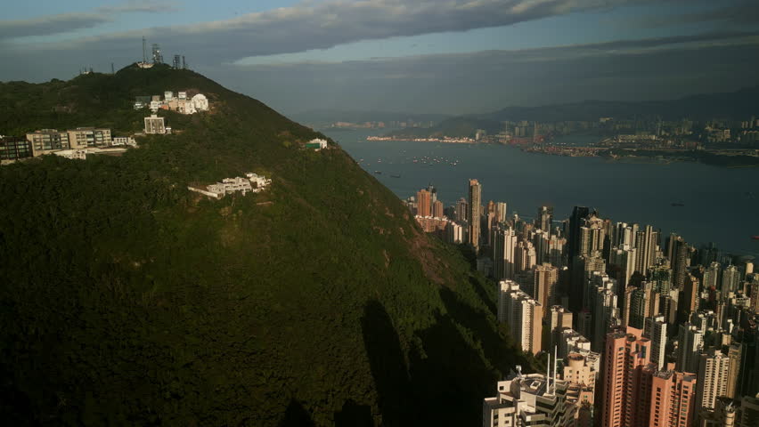 Aerial view of Hong Kong skyline with Victoria Peak hill, modern skyscrapers and Victoria Harbor in background. Urban cityscape of Asia mixing nature and architecture.