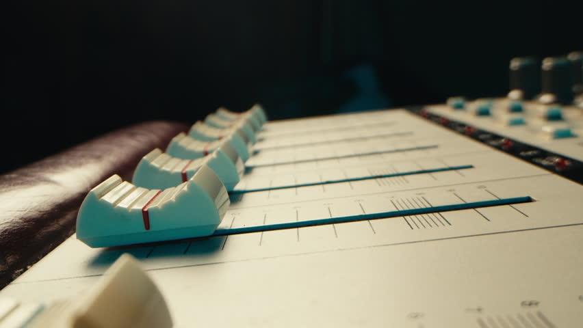 Music studio close up, Close up hands shot of sound engineer using mixing console, remote control for adjusting sound, audio mixer. Musician creates music, makes remix for DJ set. Sound recording