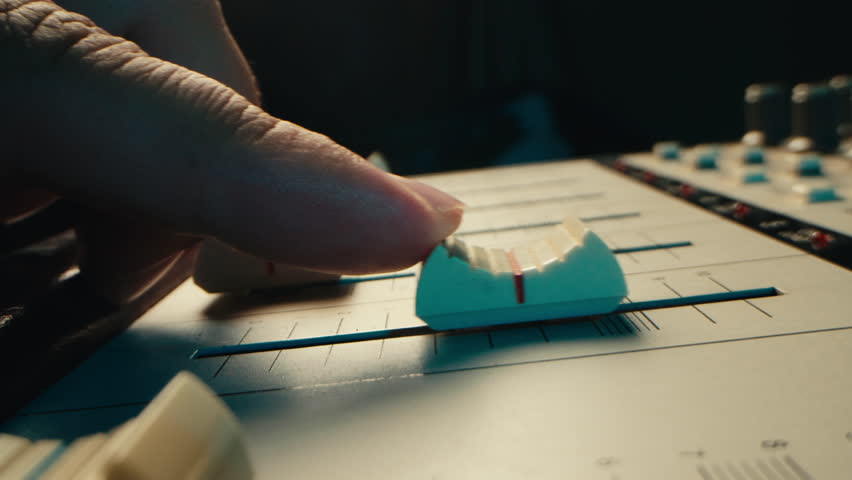 Music studio close up, Close up hands shot of sound engineer using mixing console, remote control for adjusting sound, audio mixer. Musician creates music, makes remix for DJ set. Sound recording