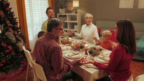 Multigenerational caucasian family gathering around dining table, joining hands in prayer before sharing festive christmas meal, expressing spiritual connection and familial love - Powered by Shutterstock - Get 15% off with code: PIKWIZARD15