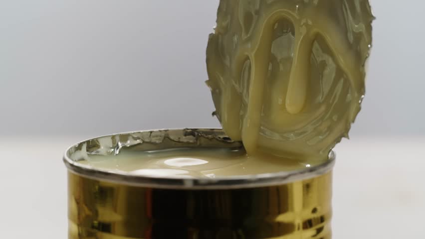 Condensed milk with sugar dessert, Open a can of a creamy ingredient, successfully revealing its delicious contents inside