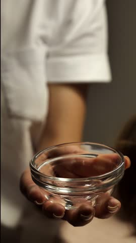 Beautician mixes cleansing exfoliating peeling gel for face skin in a bowl, close-up, top view, vertical. Rejuvenating beauty procedure in the beauty parlor.
